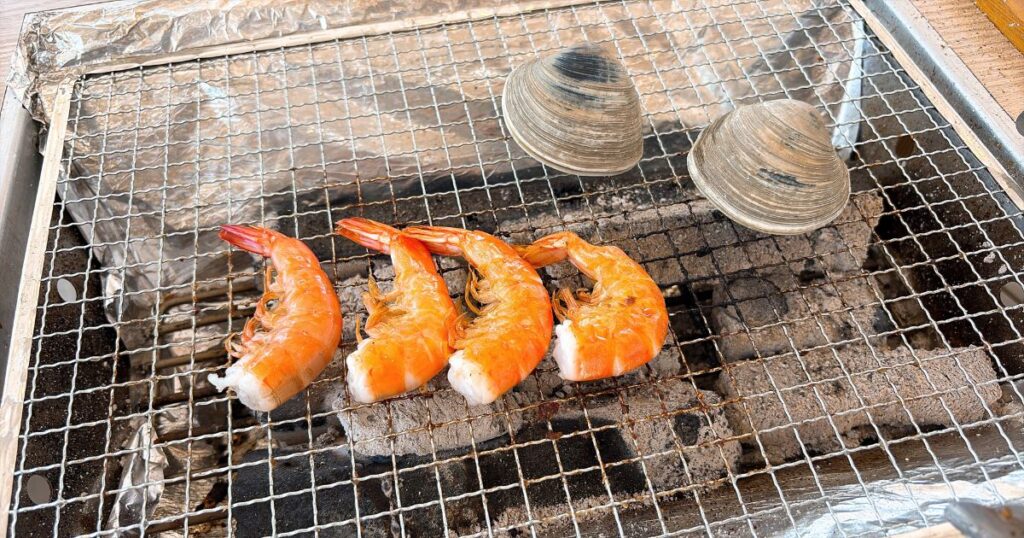 網の上で焼いているホンビノス貝とエビ