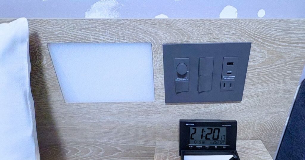 たびのホテル宇都宮ゆいの杜のダブルルームのベッドの枕元で操作できる電気のスイッチとコンセント