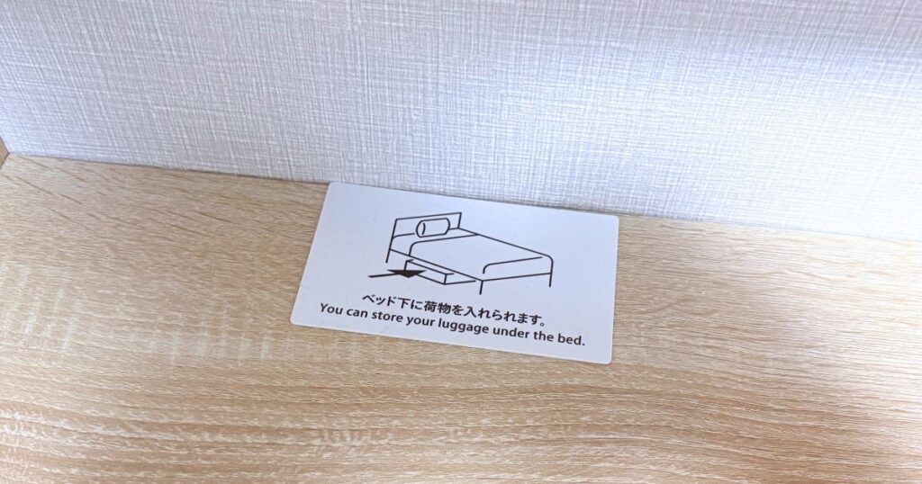 たびのホテル宇都宮ゆいの杜のダブルルームの「ベッド下に荷物を入れらます」と書かれたプレート